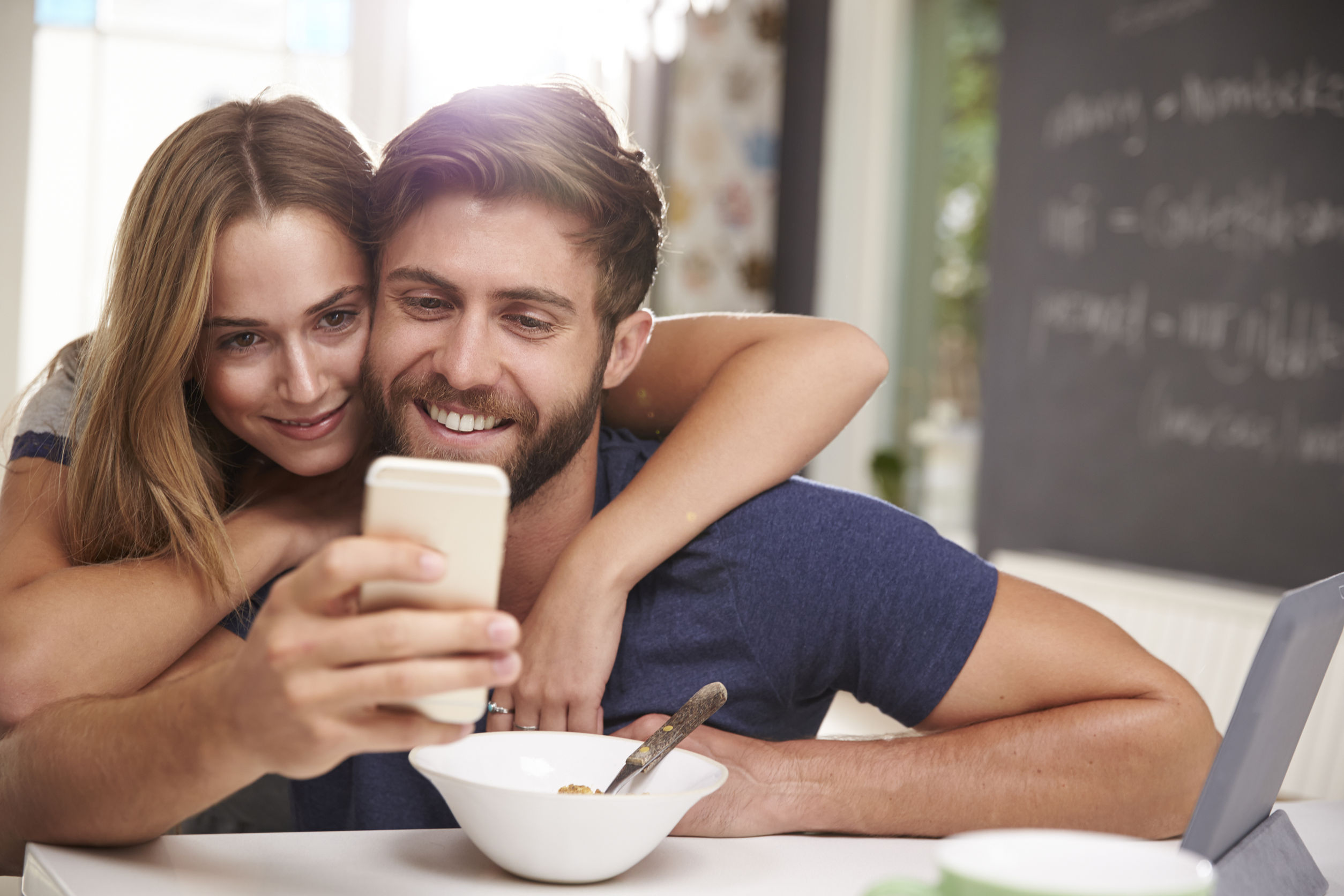 Pareja joven, sentados en su cocina mirando el telefono movil